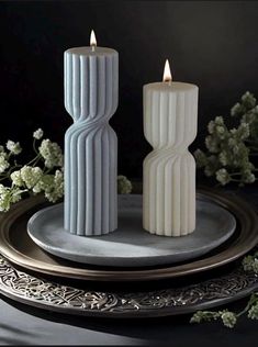 two white candles sitting on top of a plate