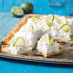 a piece of key lime pie with whipped cream and limes on the side, ready to be eaten