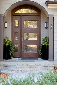 the front door to a home with two planters on each side