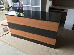 an office desk with black and brown stripes on the front, and white shelves behind it