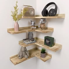 three wooden shelves with headphones, books and other items on them in a corner