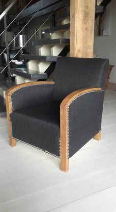 a black chair sitting on top of a hard wood floor next to a stair case