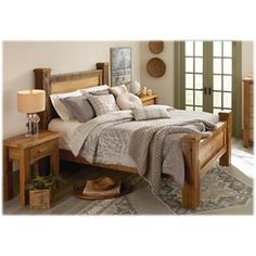 a wooden bed sitting next to a dresser and lamp on top of a rug in a bedroom