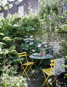 an outdoor table and chairs in the middle of a garden