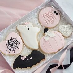 decorated cookies in a gift box with ribbon on the floor next to pink and black ribbons