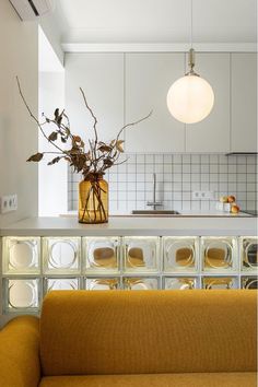 a vase with some flowers sitting on top of a counter next to a couch in a kitchen