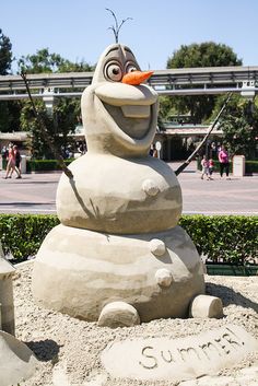 the sand sculpture is made to look like a cartoon character with an orange nose and beak