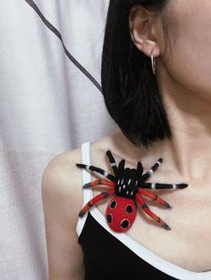 a woman wearing a red and black spider necklace