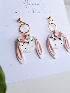 the earrings are decorated with pink flowers and gold hoops on top of white paper