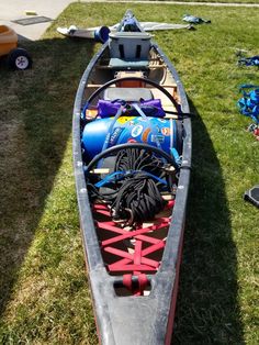 a canoe is sitting on the grass with other items in its storage bag and water bottle