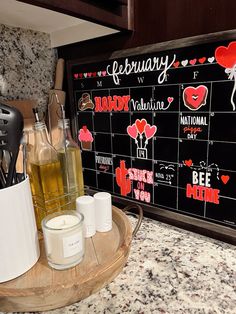 a wooden tray topped with bottles of liquid next to a chalkboard that says valentine's day