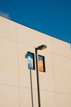 two windows on the side of a building with a sky in the window behind them