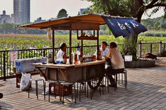 some people are sitting at a table under an umbrella