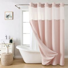 a bath tub sitting next to a window covered in a pink shower curtain and matching rug