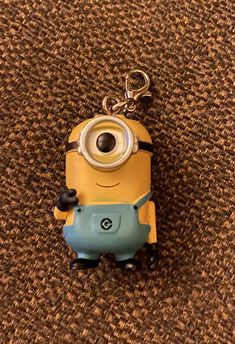 a yellow and blue minion keychain sitting on top of a brown carpet