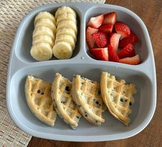 a plate with waffles, bananas and strawberries in it on a table