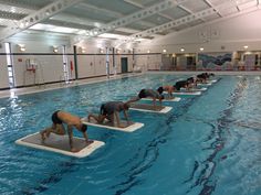 people are doing yoga in an indoor swimming pool with their backs turned to the side