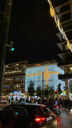 cars are parked on the street in front of a building with christmas lights hanging from it's sides