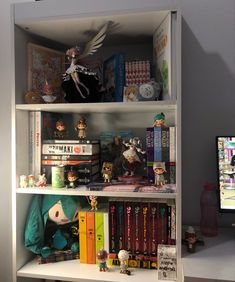 a book shelf filled with books and figurines on top of eachother