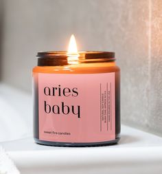 an orange candle sitting on top of a white counter next to a wall with the words orbies baby written on it