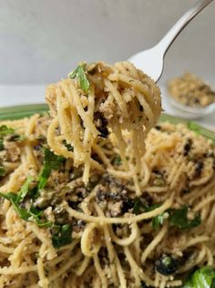 a fork full of pasta with spinach and parmesan cheese on the side