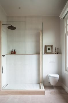 a bathroom with a shower, toilet and sink in it's center wall next to a window