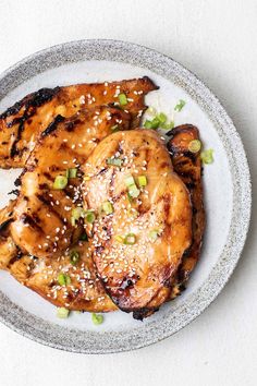 grilled chicken with sesame seeds and green onions on a plate