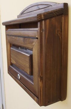 a wooden mailbox mounted to the side of a wall