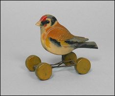 a small bird sitting on top of two yellow and brown wheels with one red head