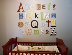 a baby crib in front of a wall with letters on it