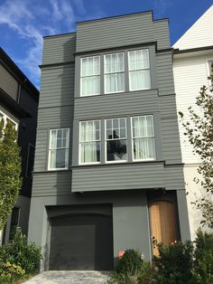 a large gray house with three windows on the top floor and two garage doors at the bottom