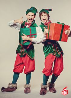 two men dressed in green and red are holding presents while posing for the camera with their mouths open