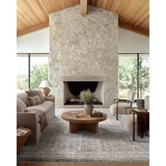 a living room filled with furniture and a fire place in front of a stone wall