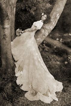 an old fashion photo of a woman leaning against a tree