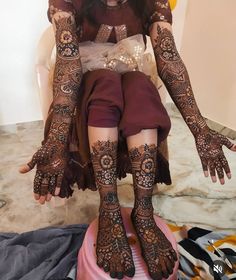 a woman sitting on top of a stool covered in henna