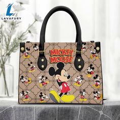 Mickey Mouse Brown Pattern Premium Leather Handbag It’s a practical accessory for fashion-conscious individuals on the go and makes an excellent gift choice for special occasions. The bag is crafted with care and attention to detail, made of high-quality PU leather with a soft microfiber layer that protects your belongings. It features two zippered pockets, one flat pocket, and one detachable pocket, making it ideal for organizing your essentials. The bag is spacious enough to hold everyday item Gift Satchel With Double Handle And Dust Bag, Portable Leather Tote Shoulder Bag, Portable Leather Handheld Bags, Portable Handheld Leather Bags, Portable Leather Handheld Satchel, Portable Handheld Leather Satchel, Leather Tote Satchel, Portable Faux Leather Bag For Everyday Use, Portable Faux Leather Rectangular Bag