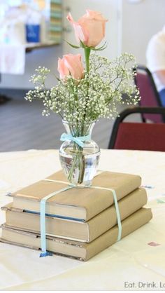 a vase filled with pink roses sitting on top of two books next to each other