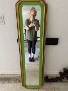 a woman taking a selfie in front of a mirror with her cell phone on the floor