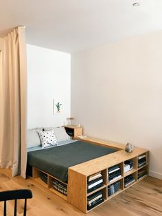 a bed sitting on top of a wooden floor next to a book shelf filled with books