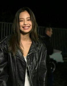 a woman wearing a black leather jacket smiling