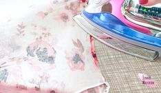 a person ironing fabric with a pink and blue iron