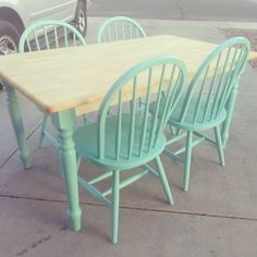 a wooden table and four chairs sitting on the sidewalk next to a white car parked in front of it