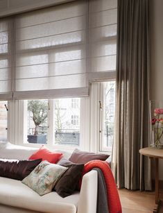 a living room filled with furniture and windows covered in roman blind shades on top of them