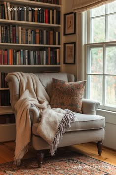 a chair with a blanket on top of it in front of a bookshelf