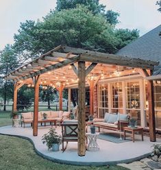 an outdoor patio with lights strung up on the pergolated area and seating areas