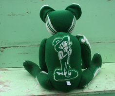 a green teddy bear sitting on top of a wooden bench