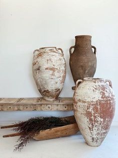 three vases sitting on top of a wooden shelf next to a pile of twigs