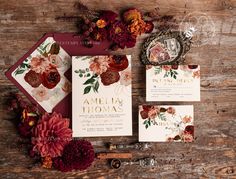 the wedding stationery is laid out on top of an old wooden table with flowers