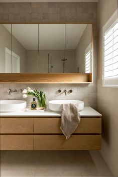 a bathroom with two sinks, mirrors and a towel on the counter in front of it