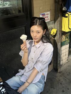 a woman sitting on the ground eating an ice cream cone